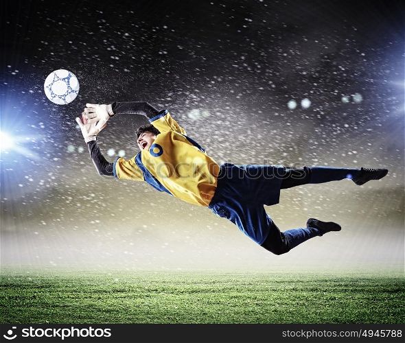 Goalkeeper catches the ball. Goalkeeper catches the ball . At the stadium, in the spotlight.