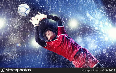 Goalkeeper catches the ball. Goalkeeper catches the ball . At the stadium, in the spotlight.