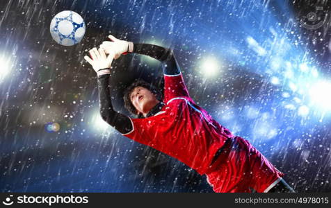 Goalkeeper catches the ball. Goalkeeper catches the ball . At the stadium, in the spotlight.