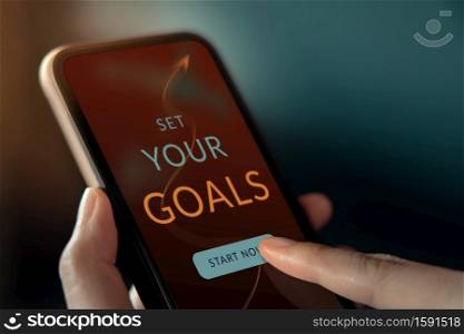 Goals and Strategy Concept. Hand Making a Personal Goal via Mobile Phone application. Closeup shot