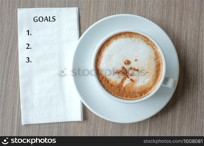 GOALS word with hot cappuccino coffee cup on table background at the morning. New Year New Start, Resolution, Solution, Strategy and Mission concept