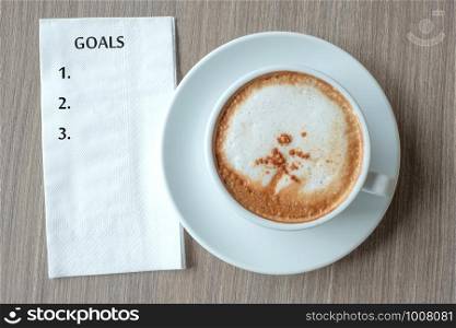 GOALS word with hot cappuccino coffee cup on table background at the morning. New Year New Start, Resolution, Solution, Strategy and Mission concept