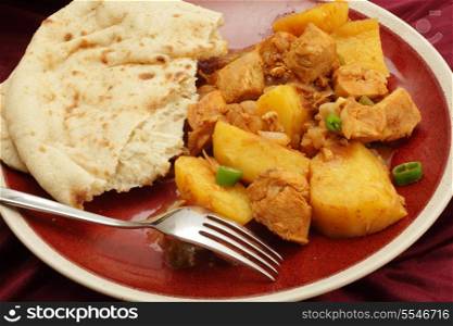 Goan chicken and potato vindaloo curry, cooked in a vinegar and spice sauce and served with a slice of flat bread