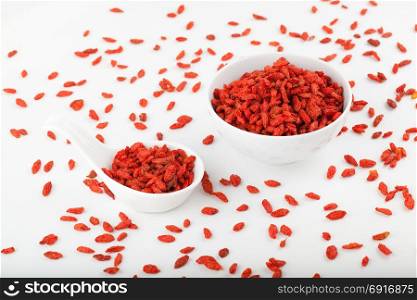 Goji berry in white bowl and spoon isolated on white background