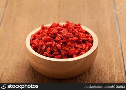 Goji berry in wooden bowl on wood background