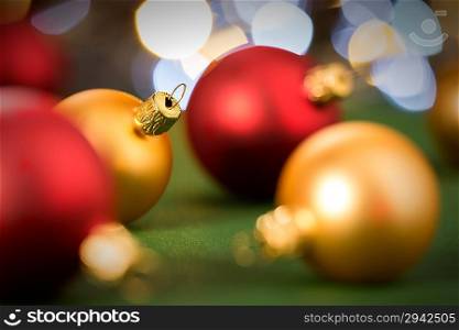 Gold and red christmas baubles on green lights background
