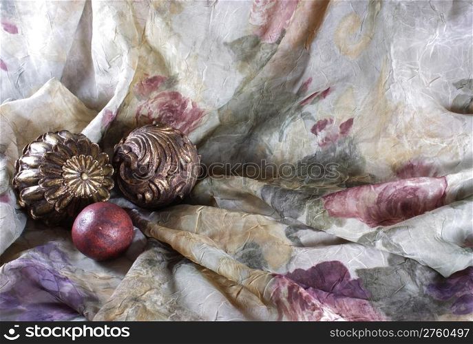 Gold balls arranged on a purple, beige, maroon and green fabric to be used as a background