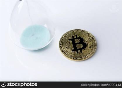 Gold bitcoin and hourglass on a white background.. Bitcoin gold and the hourglass.