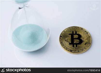 Gold bitcoin and hourglass on a white background.. Bitcoin gold and the hourglass.