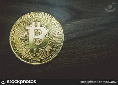 Gold Bitcoin coin on wooden floor background.