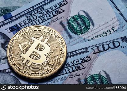 Gold bitcoin on hundred dollar bills. The concept of virtual business and currency.. Gold bitcoin on hundred dollar bills