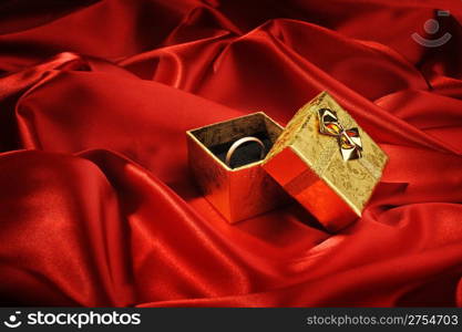 Gold boxes with a wedding ring on red silk