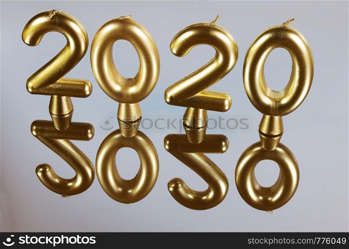 Gold candle background for 2020 year. Candles on a mirror surface with reflection.. Gold candle background for 2020 year