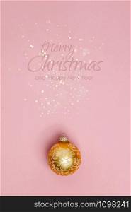 Gold Christmas ball on pink background. Flat lay, top view