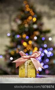Gold Christmas gifts with pink bow, with Christmas tree bokeh lights background and copy space, Holiday, present xmas concept space for text. Gold Christmas gifts with pink bow, with Christmas tree bokeh lights background and copy space, Holiday, present xmas concept