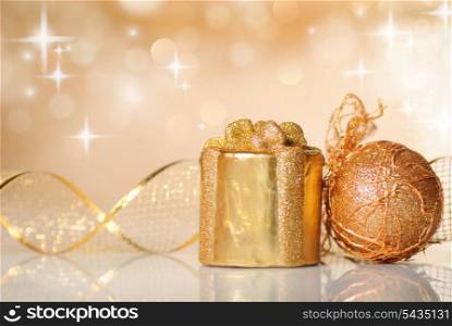 Gold Christmas ribbon ornament on background of defocused golden lights. Shallow DOF.