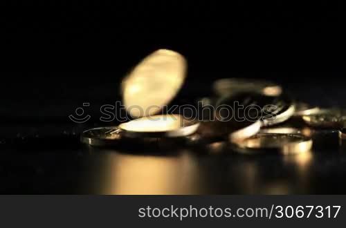 Gold coins falling over dark background. Macro shot.