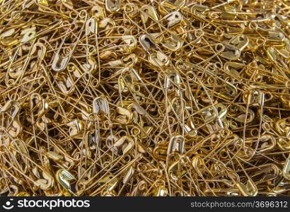 Gold colored safety pins pile closeup as background