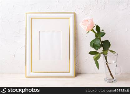 Gold decorated frame mockup with tender pink rose in glass. Empty frame mock up for presentation artwork.. Gold decorated frame mockup with tender pink rose in glass