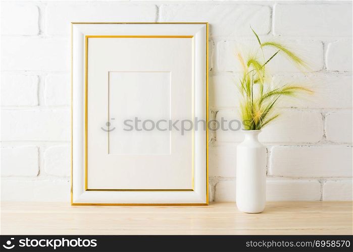 Gold decorated frame mockup with yellow and green wild grass ears in styled vase near painted brick wall. Empty frame mock up for presentation design. Template framing for modern art. . Gold decorated frame mockup with yellow green wild grass ears