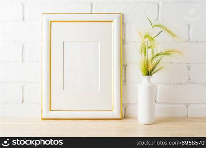 Gold decorated frame mockup with yellow and green wild grass ears in styled vase near painted brick wall. Empty frame mock up for presentation design. Template framing for modern art. . Gold decorated frame mockup with yellow green wild grass ears
