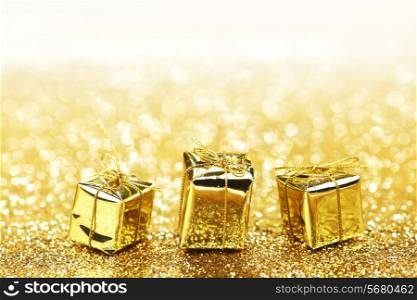 Gold decorative boxes with holiday gifts on abstract gold background with white copy space
