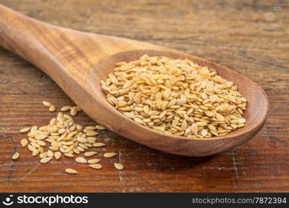 gold flax seeds on a wooden spoon against a grunge wood