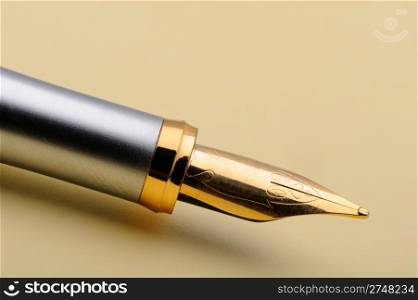 Gold fountain pen closeup. On a yellow paper