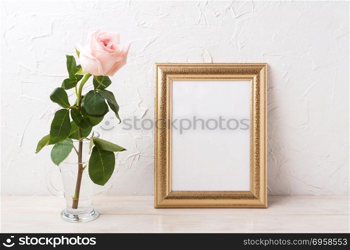 Gold frame mockup with tender pale pink rose in glass. Empty frame mock up for presentation artwork.. Gold frame mockup with tender pale pink rose in glass
