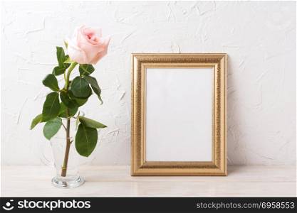 Gold frame mockup with tender pale pink rose in glass. Empty frame mock up for presentation artwork.. Gold frame mockup with tender pale pink rose in glass