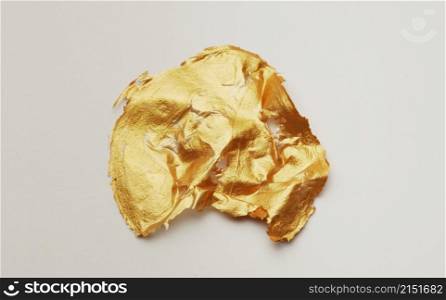 Gold glitter and bronze color blot. Abstract torn piece of metal leaf (potal) paper on white background.