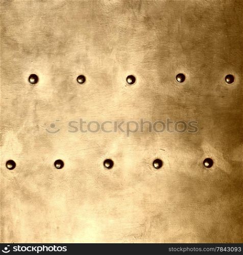 Gold grunge metal plate or armour texture with rivets as background square format