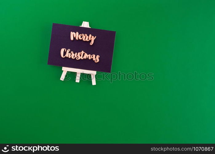 Gold merry christmas on blackboard top view on green paper background.minimal style greeting card.celebrate hoiday concept