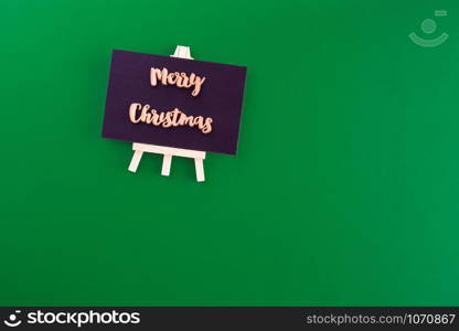 Gold merry christmas on blackboard top view on green paper background.minimal style greeting card.celebrate hoiday concept