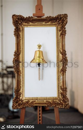 gold mirror frame with gold bell on white background. wedding decoration. selective focus. gold mirror frame with gold bell on white background. wedding decoration. selective focus.