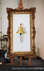 gold mirror frame with gold bell on white background. wedding decoration. selective focus. gold mirror frame with gold bell on white background. wedding decoration. selective focus.