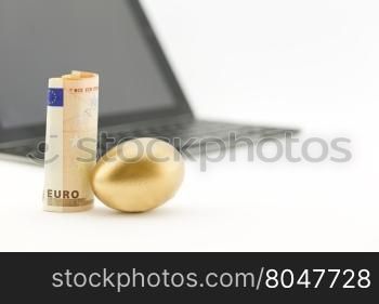 Gold nest egg next to euro currency with shallow depth of field view of technology reflects successful investing.
