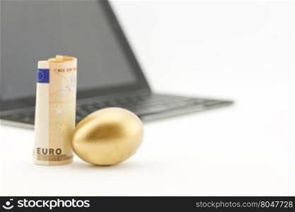 Gold nest egg next to euro currency with shallow depth of field view of technology reflects successful investing.