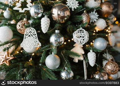 Gold, silver and white Christmas toys on the Christmas tree close-up. Festive background for copy space