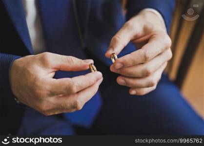 Gold wedding rings in the hands of the groom.. The groom holds the gold wedding rings with his fingers 2560.