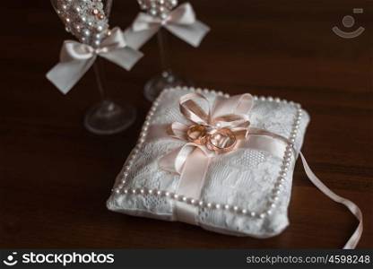 gold wedding rings lie on a cushion on a brown table