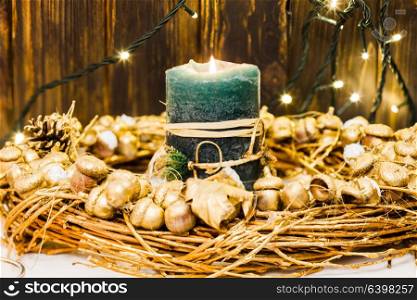 Golden acorns and pine cones in glasses and wreath, candlelight and decor for Christmas. Golden Christmas decor