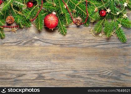 Golden and red Christmas decorations and fir branch on a wooden background
