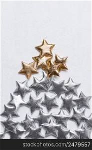 Golden and silver stars in a tree shape chtristmas tree concept on a white textured background