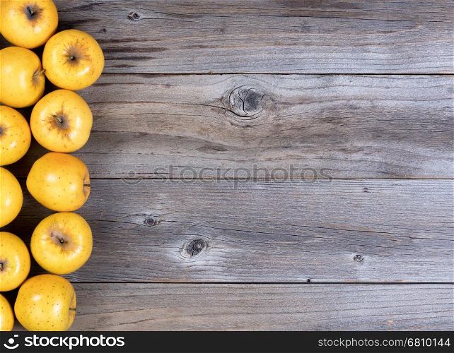 Golden apples, on left hand side, on rustic wooden boards