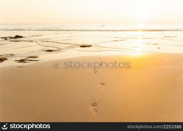 Golden beach, footprints and wave at sunset time. Tropical sand beach, Lanta Island, Thailand.