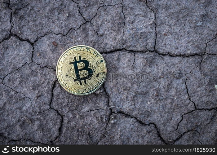 Golden Bitcoin Coin on dry cracked ground background. Financial Crisis concept Bitcoin cryptocurrency.