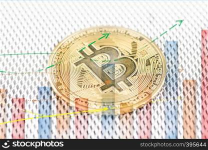 Golden Bitcoin, cryptocurrency physical coin and defocused chart foreground. Virtual cryptocurrency concept