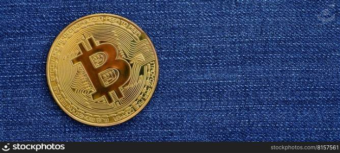 Golden Bitcoin lies on a blue jeans fabric. New virtual money. New crypto currency in the form of the coins