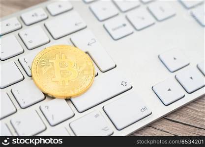 Golden bitcoin lying on a white keyboard . Golden bitcoin on a keyboard